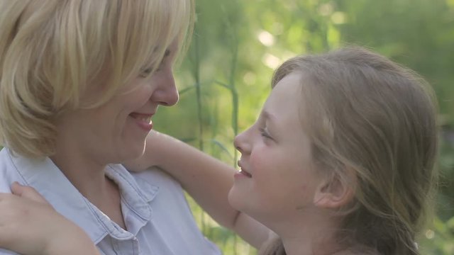 Cheerful blonde mother and child looking at each other, touching noses, smiling