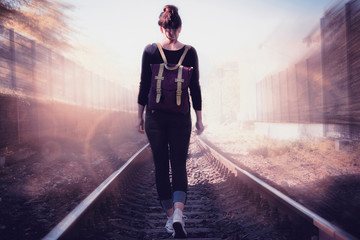 Conceptual image of woman walking into the light on railway tracks.