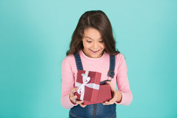 What a surprise. Child surprised excited holds gift box turquoise background. Kid girl surprised...
