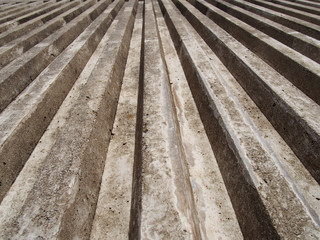 close up of cast concrete with vertical ribbed texture with a converging view in sunlight and shadow
