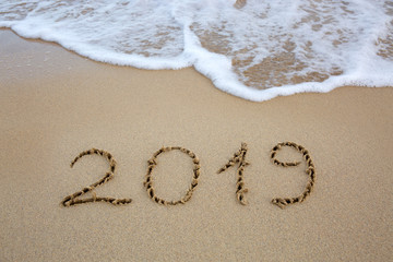 Year 2019 written at the caribbean sand beach with sea wave .
