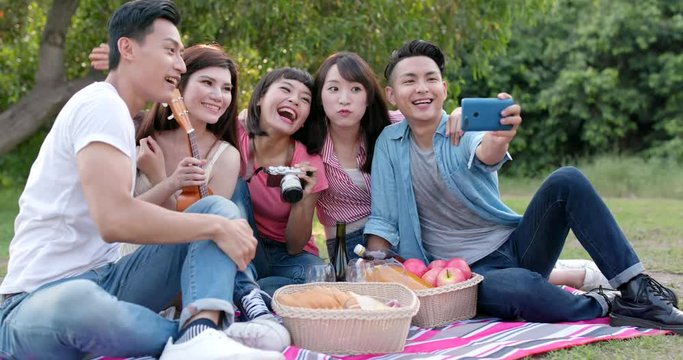 Asian Young friends taking selfie on cellphone in the park