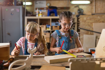 Two young girls doing woodwork in a workshop
