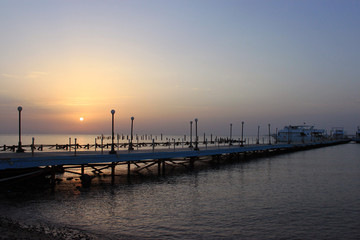 Sunrise on the sea. Pier stretching into infinity. Morning sun rays. Red sea, Safaga, Egypt.