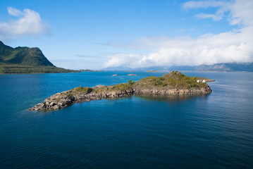 Naklejka premium Masterpieces of nature. Island stony surrounded sea water in Norway. Best nature places to visit in Norway. Seascape with island on sunny day. Serenity and idyllic. Island stony cliffs coast