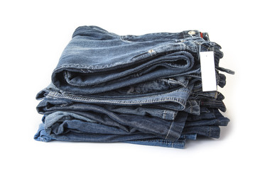 Pile of blue jeans with blank price tag on the white