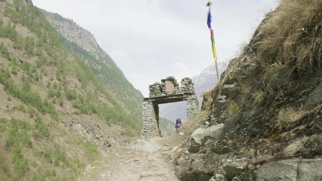 Backpackers walk through the gate on nepalese path around the Manaslu mountain.