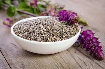 Obraz na płótnie Canvas Chia seed healthy superfood in bowl with flower over wooden table
