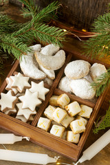 Fototapeta na wymiar Assorted Christmas cookies: cinnamon stars, vanilla crescents, stollen and ginger cubes in a wooden box. Rustic style.