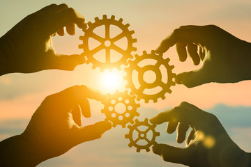 Business concept idea. four hands of businessmen collect a puzzle from gears. Cooperation, teamwork, strategy, creativity, innovation.