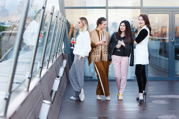 Four successful young female employees of large business companies celebrate a corporate party with a glass of wine in hands on an outdoor terrace