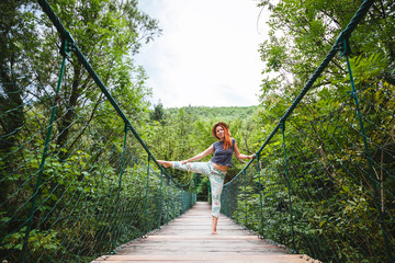 Young woman in the forest on the wooden bridge enjoying summer