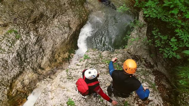 Aerial view of a group canyoning and jumping in the water on the Soca river.