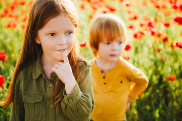 Little red-haired children pick red flowers in the field.