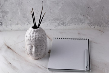 Buddha head with incense  on a marble background