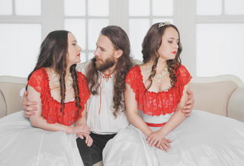 Two beautiful woman and man in medieval costumes
