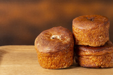 Three cupcakes without cream on a wooden tray. Background is brown. Copy space.