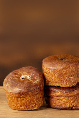 Three cupcakes without cream on a wooden tray. Background is brown. Copy space. Vertical shot.
