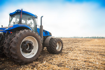Fototapeta premium Blue tractor on the background of an empty field