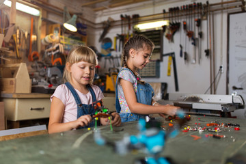 Small girls building toy construction machine
