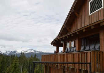 partial view of a chalet type building during off season, chair stacked up on the balcony, snow covered Mountain peaks in the Background, Vancouver Island Mountain ranges, British Columbia Canada