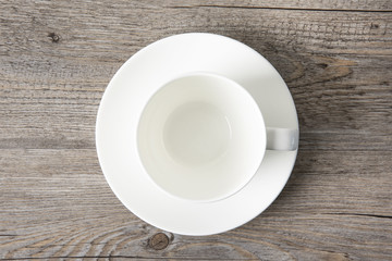 A white cup is empty on a wood background. Top view. Copy space.