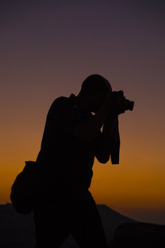 silhouette of a photographer with camera with sunset and sky in background