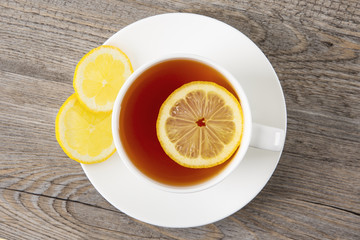 Tea with lemon in a white mug on a wooden table. Top view. Copy space.