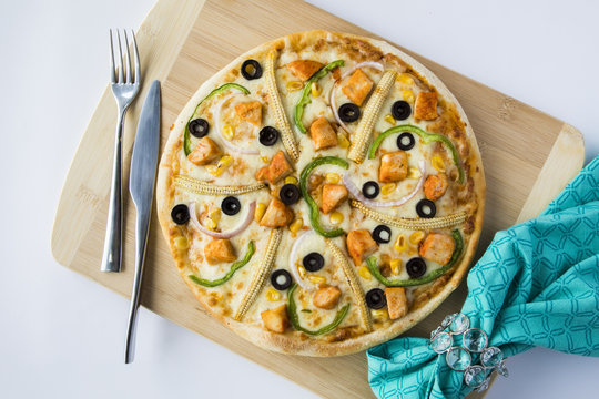 Italian veg pizza on a wooden platter along with napkin, fork and knife