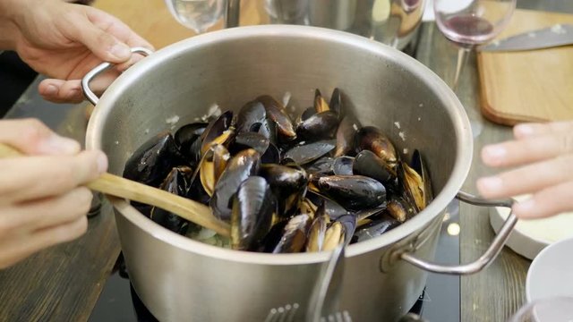Close-up shot of mussels are being stewed in a saucepan on an electric stove. 4K