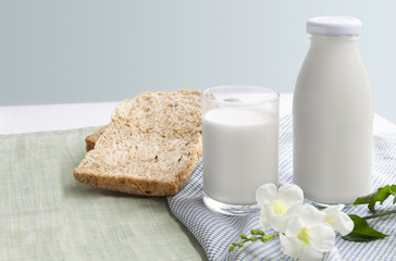 Obraz na płótnie Canvas A bottle of milk and glass of milk with sliced bread on blue and green cloth isolated on white table background for food and healthy concept. with copy space for text.