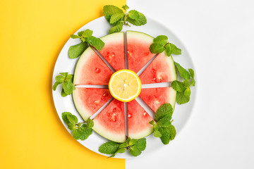 Sliced watermelon on plate with mint and lemon, ready to eat.