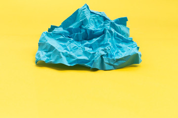 Blue crumpled paper on yellow background, abstract