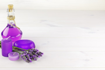 Spa products, aroma candle and lavender flowers on a wooden background