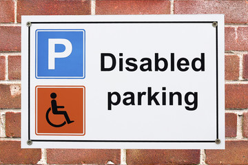 Disabled parking sign on brick wall with parking and wheelchair symbols