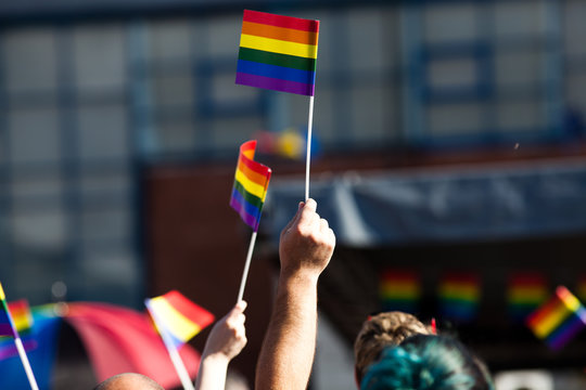 crowd waving rainbow flags at pride parade