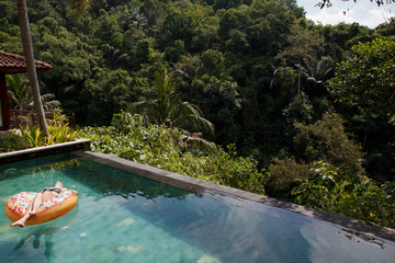 girl in the tropic pool at inflatable ring