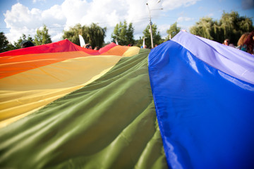 people holding giant rainbow flag at pride parade - LGBT symbol