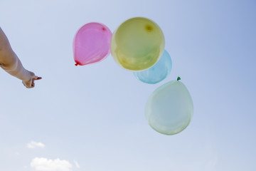 Lots of colorful balloons in the hand against sky