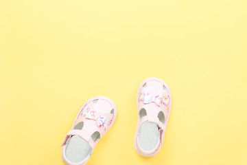 Pink baby girl summer sandals close up on yellow background.