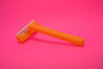On a bright colorful pink paper background is located and placed a yellow disposable shaving machine