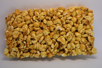 On a white paper background is located and placed from a delicious and sweet grilling of air corn kernels, popcorn with caramel