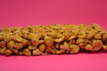 On a bright colorful pink paper background is located and placed from a delicious and sweet grilling of air corn kernels, popcorn with caramel
