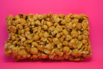 On a bright colorful pink paper background is located and placed from a delicious and sweet grilling of air corn kernels, popcorn with caramel