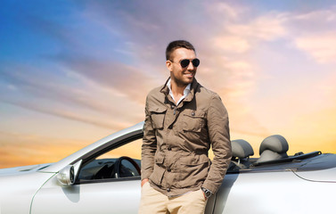 road trip, travel and people concept - happy man near convertible car over sky background