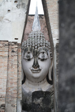 Ancient marvellous stone buddha head statue surrounding by triangle great stone wall at Wat Sri Chum, Sukhothai, Thailand, smilling peace buddism location , travel destination poster backgrounds,