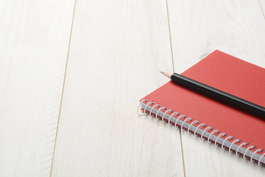 Cuaderno y l&aacute;piz sobre fondo de madera blanca