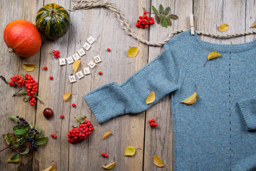 Autumn fall flat lay, top view. Warm knitted sweater, Fall Leaves, chestnuts, rowan berry and pumpkin with  inscription 