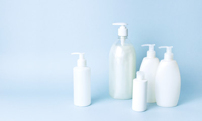 Cosmetic bottle containers on a blue minimalistic background flat lay. Blank label for branding mock-up. Natural beauty product concept.