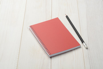 Cuaderno y lápiz sobre fondo de madera blanca